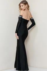 Vestido largo de fiesta color negro, con diseño strapless y ajuste al cuerpo. Presenta un detalle de pedrería brillante en la parte superior del busto y una falda con caída fluida.