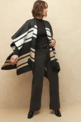 Poncho con diseño a rayas en tonos negro, blanco y beige.