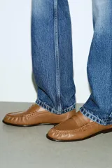 Mocasín color tostado con efecto soft, detalle de antifaz y copete subido. Presenta fruncido en la parte delantera y acabado en punta redonda. Suela de 1 cm de altura.