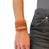Pulsera brazalete con base metálica ajustable, cubierta de lentejuelas color salmón y strass dorados.