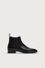 Bota Chelsea de cuero negro con paneles elásticos laterales, tirador trasero y punta fina, con suela de tacón bajo.