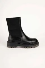 Bota baja de mujer estilo paddock, color negro, con suela track gruesa y caña de tejido elástico.