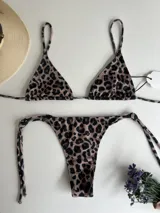 Conjunto de bikini con estampado animal print, compuesto por un corpiño triangular con tiras largas para atar en la cintura y una bombacha colaless con tiras para atar en los costados.