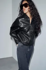 Chaqueta estilo bomber de efecto piel en color verde oliva, con cuello solapa, cierre frontal con cremallera, mangas largas y bajo elástico.