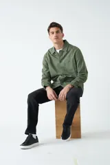Sobrecamisa verde militar de algodón grueso tipo canvas, con cuello clásico, cierre frontal con botones, dos bolsillos de parche en el pecho con solapa abotonada y dos bolsillos de parche en la parte inferior.