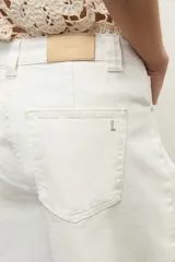 Bermuda de jean color crudo, de tiro medio/alto, con bolsillos laterales y traseros, y diseño amplio hasta las rodillas.