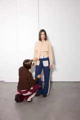Camisa de tela afelpada color beige con nudo en el cuello, mangas abullonadas con lazos en los puños y bolsillos frontales con tapa.