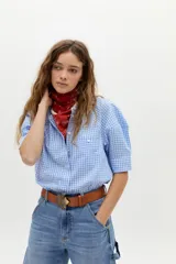 Camisa blanca de algodón con cuello mao, botonera oculta, mangas cortas estilo raglán con cortes estructurados y un bolsillo frontal con cierre.