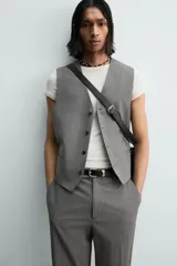 Chaleco de traje regular fit confeccionado en tejido con lana, con cuello en pico, cierre frontal de botones y bolsillos de vivo en la cintura. Presenta forro interior con diseño de rayas.