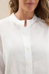 Camisa de lino de color blanco, corte relajado, con cuello mao y cierre frontal de botones.