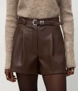 Short de poliuretano color negro, de corte recto con pinzas frontales y largo corto. Incluye un cinturón fino con hebilla y pasantes metálicos.