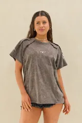 Remera marrón con efecto acid wash, corte oversize, mangas cortas caídas, costuras decorativas expuestas y pequeño logo bordado en el pecho.