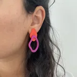 Par de aros colgantes con formas abstractas en acrílico color naranja y fucsia.