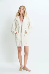 Saco de textura tipo peluche, color crema, con capucha y bolsillos frontales. Presenta un estampado sutil de corazones rojos dispersos por toda la prenda.