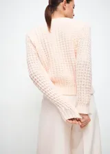 Jersey de punto texturizado color rosado claro, con cuello redondo y mangas largas.