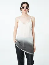 Top blanco con breteles finos y terminaciones desflecadas. Diseño irregular con degradé a gris oscuro en el ruedo.