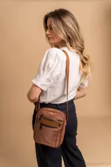 Morral bandolera color lila con correa ajustable, dos bolsillos frontales con cierre y dos bolsillos internos.