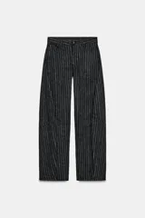 Pantalón de tiro medio con diseño balloon, confeccionado en tejido con patrón de rayas verticales. Presenta cintura con trabillas, cierre frontal con cremallera y botón, y cinco bolsillos.