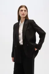 Blazer blanco de corte holgado, con cuello solapa, doble botonadura y bolsillos delanteros.