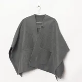 Ruana gris de tejido punto con bolsillos frontales aplicados, escote en V y detalle de presilla con botón en el cuello.