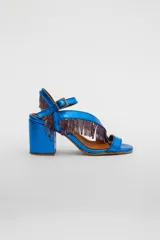 Sandalias de cuero gamuzado color azul, con taco ancho y tiras cruzadas en el empeine decoradas con flecos de cuentas. Cuentan con pulsera regulable al tobillo con hebilla metálica.