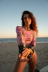 Entero de lycra reciclada con protección solar SPF 50, de manga larga con estampado floral en tonos rosa, amarillo y negro. Tiene escote redondo, cuello a la vista y cierre en la espalda.