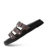 Sandalias planas Miss Carol modelo Nevada, color marrón, con tres tiras en el empeine decoradas con tachas metálicas plateadas. Una de las tiras cuenta con una hebilla de ajuste lateral. Poseen suela y plataforma baja de color negro.