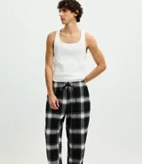 Pantalón de pijama de corte recto confeccionado en franela de algodón con estampado de cuadros en tonos blanco y negro. Presenta cintura elástica con cordón de ajuste para mayor comodidad.