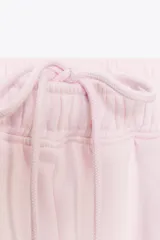 Pantalón de felpa de tiro alto con cintura elástica y corte recto. Cuenta con bolsillos laterales ocultos en la costura y bajo ajustable con cordón elástico y stoppers.