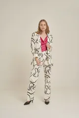 Pantalón de vestir de corte recto, con diseño estampado abstracto en blanco y negro, bolsillos laterales y cierre frontal.