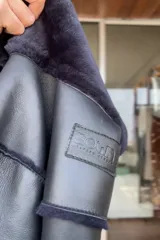 Campera reversible de corte recto y largo a la cadera. Un lado presenta un acabado de napa negra, mientras que el otro lado está confeccionado en piel sintética de color azul noche, extremadamente suave al tacto. Cuenta con mangas largas y un diseño versátil y elegante.