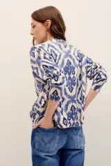 Sweater de punto color crudo con estampado geométrico en tonos azules, cuello redondo y mangas largas.