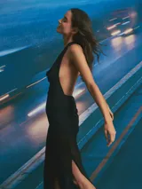 Vestido largo negro con escote drapeado tipo halter y falda transparente.