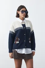 Cardigan de tejido jacquard en color azul marino y blanco, con diseño de conejitos en los laterales, cierre frontal con botones y cuello redondo.