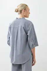 Camisa de jean a rayas verticales azules y blancas, con cuello mao y mangas largas.