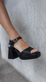 Sandalias negras de plataforma con taco ancho y pulsera al tobillo con hebilla metálica.