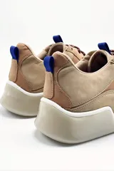 Zapatillas de cuero color tostado con detalles en marrón y lila.