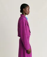 Blazer corto color fucsia de lino y viscosa, con solapas de muesca, cierre cruzado con dos botones, bolsillo en el pecho y forro completo.