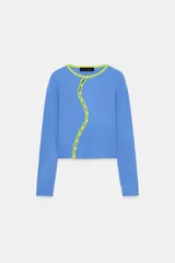 Chaqueta de punto color azul, con cuello redondo y manga larga. Presenta acabados en contraste de color verde neón y cierre frontal cruzado con botones.