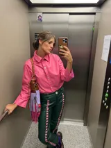 Camisa de cuero rosa con cuello clásico, cierre frontal de botones y mangas largas.