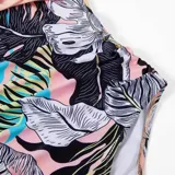Malla entera de color verde oscuro, combinada con un diseño floreado en la parte inferior. Presenta escote halter cruzado y fruncidos en la zona del abdomen.