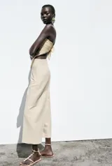 Pantalón de lino negro, de tiro alto, con bolsillos delanteros de vivo, pernera recta y cierre frontal con cremallera, botón interior y gancho metálico.