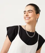 Enterito corto de tirantes finos ajustables, color blanco con rayas verticales finas, escote en V y bolsillos delanteros.