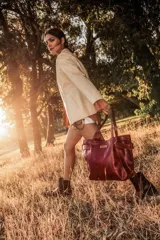 Cartera de cuero color bordó, tipo tote bag, con doble asa de hombro y hebillas decorativas a los costados. Incluye doble bolsillo y colgante interno para llaves.