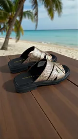 Sandalia plana de cuero con grabado efecto reptil en tono peltre, tiras cruzadas en el empeine, base y plantilla negra con aplique de logo metálico triangular y detalles de arte pintados a mano.