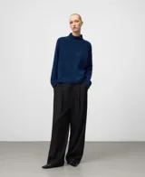 Jersey de punto para mujer con cuello chimenea y mangas raglán, confeccionado en una mezcla de lana merino y alpaca. Presenta un corte holgado de líneas redondeadas y una textura suave con pelo.