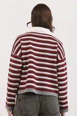 Sweater de tejido bremer con diseño de rayas horizontales en tonos vino, gris y blanco. Presenta cuello polo con solapa abotonada, mangas largas y corte holgado.