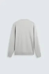 Jersey color crudo de tejido de punto, con cuello redondo y mangas largas. Corte amplio y terminaciones en rib.