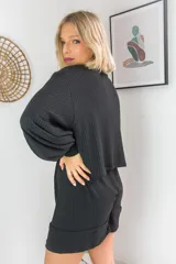 Conjunto de dos piezas en color crema, compuesto por un buzo de cuello alto, mangas largas abullonadas y ajuste en la cintura, junto con un short de tiro alto con terminaciones al corte.