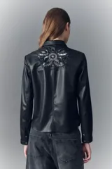 Camisa entallada de símil cuero negro con cuello camisero, botones a presión con logo y bordados florales con lentejuelas en la parte superior delantera.